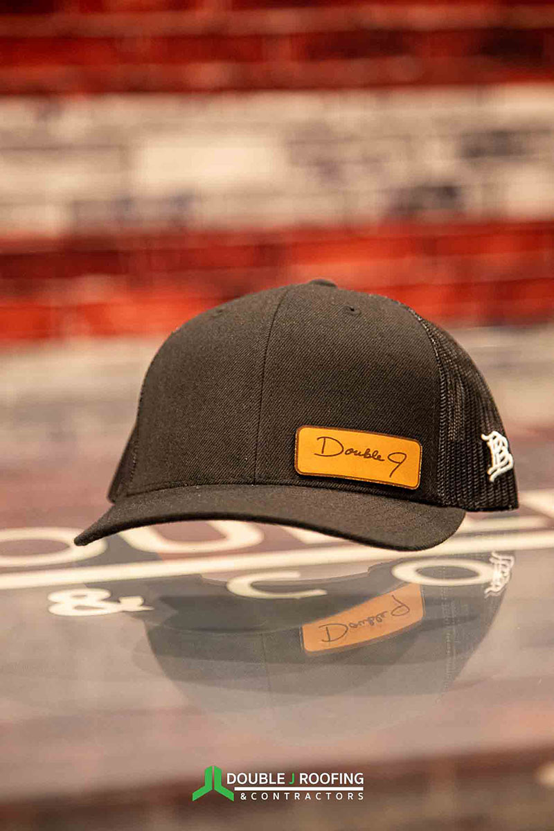 Dark gray hat with Double J written out in cursive on a small orange patch on the bottom right